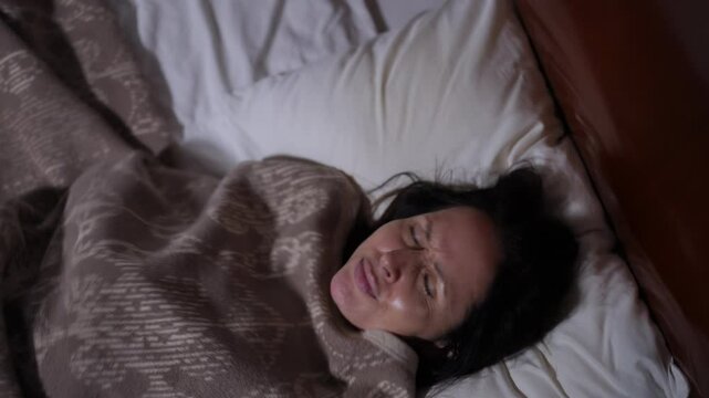 A woman is struggling with her sleep, displaying various facial expressions while wrapped up in a cozy blanket