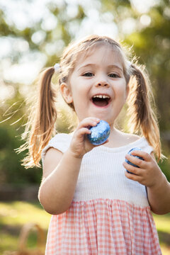 Excited little girl finds blue Easter eggs during Easter egg hunt