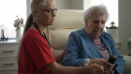 A caregiver interacts with an elderly woman, providing support and companionship in a healthcare facility during the afternoon.