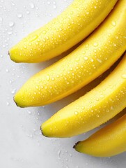 Fresh, vibrant bananas with water droplets, arranged on a clean white surface