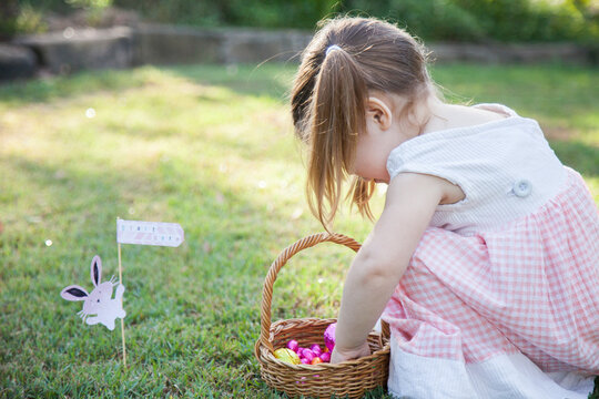 Child hunting for Easter eggs in garden on sunlit morning