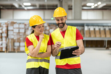 Male warehouse worker showing tablet to female colleague, explaining logistics data.