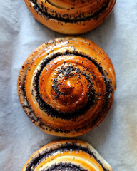 Yeast dough snail buns with poppy seeds, greased with sugar syrup. Homemade baking