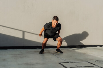 Man in black athletic wear performing a dynamic hindu squat outdoors, building functional strength...