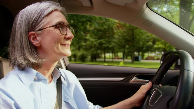 Satisfied relaxed Caucasian grandmother female elderly senior mature woman taxi driver auto car owner riding inside motorcar automobile driving steering wheel transport ride rent vehicle look around