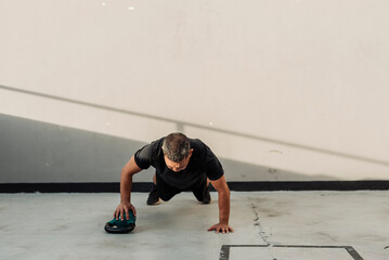 Focused middle aged man performs outdoor uneven pushups using a kettlebell for instability and...