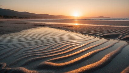 Fototapeta premium Relaxing sunset beach view with a golden hue as the sun sets behind distant hills, wet sand mirroring the sky, and rippling water textures enriching the peaceful seaside scene.