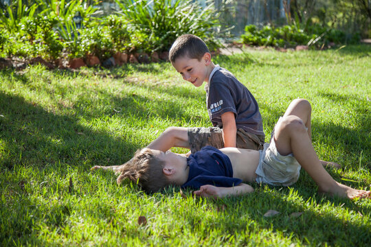 Two brothers tackling on the grass outside