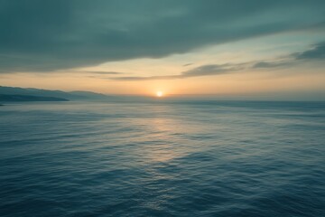 Fototapeta premium Golden sunrise bathes the expansive ocean, silhouetting the distant coastline with a tranquil, dreamy ambiance