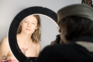 Tattoo artist creating a custom design for a young woman in a cozy Tbilisi studio. Details of the process, tattoo tools, ring light photography, and creative atmosphere