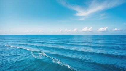 Fototapeta premium Peaceful horizontal seascape with gentle waves, clouds, and a bright blue sky on a sunny day.