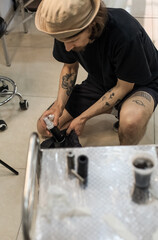 Tattoo artist creating a custom design for a young woman in a cozy Tbilisi studio. Details of the process, tattoo tools, ring light photography, and creative atmosphere