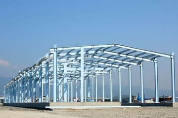 sustainable building materials,Steel framework of a large industrial building under construction against a clear blue sky.