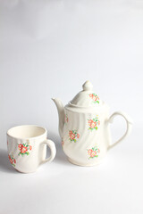 white ceramic teapot and cup with floral pattern isolated on white background