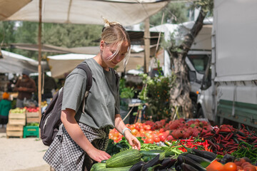 Young woman choosing fresh organic vegetables at a local market. Concept of eco lifestyle,...