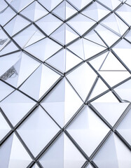 A geometric pattern of shiny triangular panels creates a modern, reflective surface, showcasing innovative architectural design