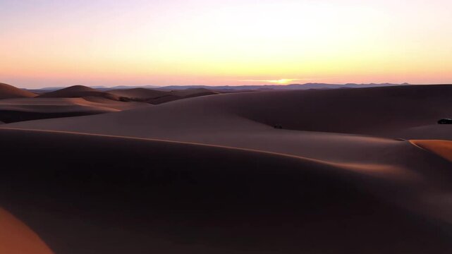Sunset over vast desert dunes with gentle slopes and deep shadows, capturing the calm beauty of the sand landscape as day transitions into night in a tranquil remote area
