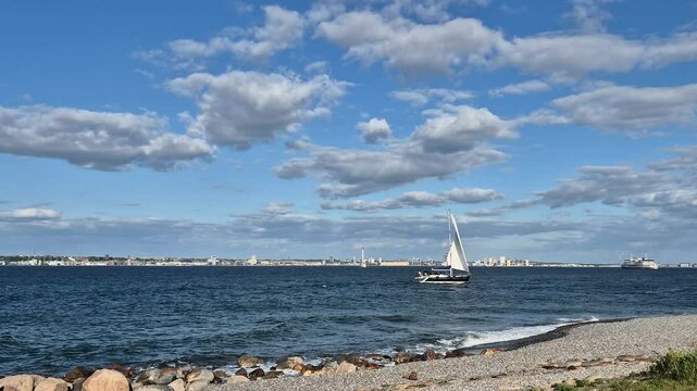 Sailboat passing the beach close to Kronborg Castle in Elsinore, Denmark