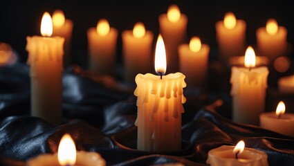 Closeup of burning candles against a black background.