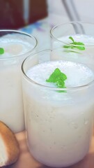 Delicious chikoo (sapodilla) milkshake served in transparent glasses with a mint garnish. A sweet, creamy tropical drink popular in Indian households during summer.
