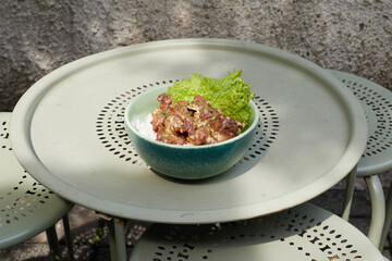 Freshly Prepared Bowl of Fried Chicken with buttermilk sauce and Lettuce Served on a Green Table Outdoors During a Sunny Day