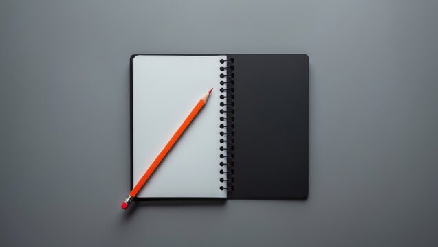 Overhead shot of an open black notebook with a red pencil on a gray surface, office notepad layout