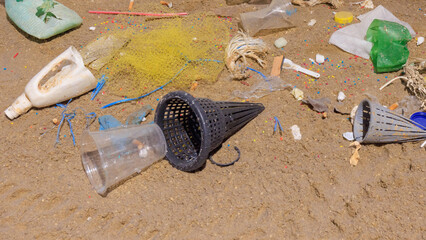 Plastic debris covers the sandy beach, illustrating the impact of pollution. Various items like...