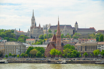 Iconic structures rise against a clear sky in Budapest, Hungary. The view showcases the blend of modern construction and historical architecture along the Danube River.