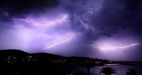 Lightning storm over Adriatic sea. Sky with lightning bolt and silhouette of a cityscape at night. Bar in Montenegro