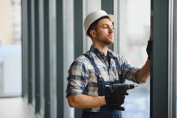 Construction worker installing window in modern building