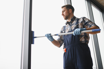 Professional cleaning service worker washing windows in office building