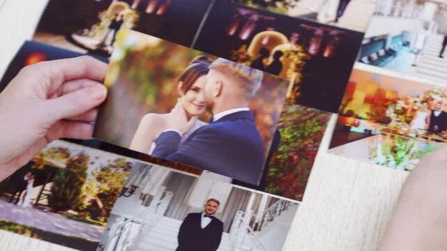 hands picking up printed wedding photos from a wooden surface