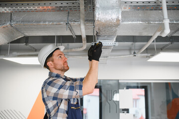Construction worker installing ventilation system in building
