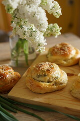 Freshly baked savory buns with green onions and sesame seeds on a wooden board