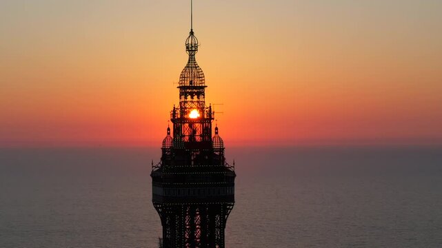 Aerial video of the Blackpool tower with the sun setting down on the sea horizon. 