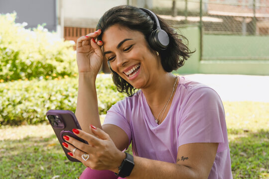 Mulher fazendo video chamada e escutando musica no parque 