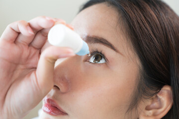 asian young woman using medical eye drops to treat dry eye and irritation.