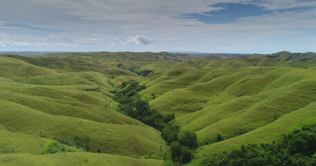Rolling green hills extend as far as the eye can see across the landscape of Sumba island,...
