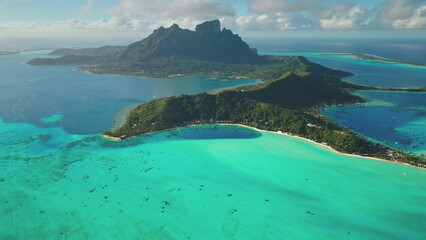 Bora Bora island beauty and tranquility tropical paradise. Turquoise coral reef lagoon, towering green mountain. Remote wild nature exotic summer vacation travel background. Drone aerial panorama shot