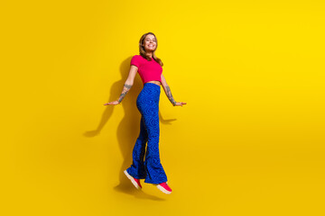 Joyful young woman in vibrant outfit posing on yellow background showcasing trendy fashion and casual style
