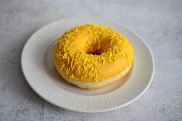 Yellow Frosted Donut with Sprinkles on White Plate mango donut