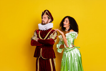 Young couple in vintage royal costumes posing with bright expressions against a lively yellow...