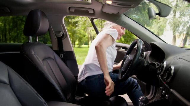 Older Caucasian mature woman senior female elderly lady car auto driver opening vehicle door sitting inside automobile fastening seat belt buckle up safety rule accident prevention protection comfort