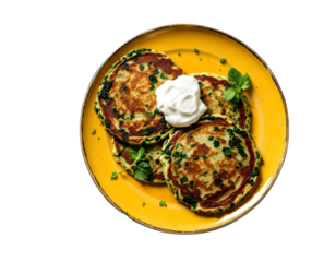 Traditional homemade spinach pancakes with sour cream on yellow plate