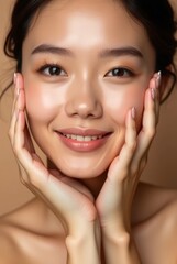 Young asian woman with glowing healthy skin holds hands on face in contemplative pose, showcasing natural beauty and radiant complexion with soft lighting and neutral background
