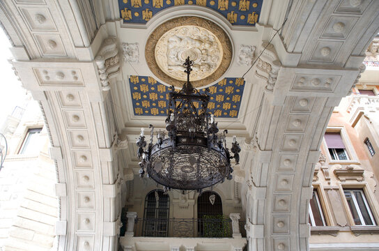 Ornate chandelier hanging from a beautifully detailed ceiling in an elegant architectural archway in Rome