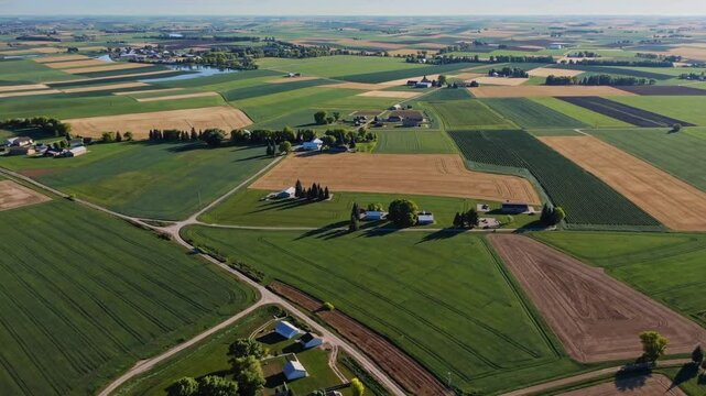 An aerial view of patchwork farmlands with crops, barns, and buildings, representing the beauty of agricultural landscapes