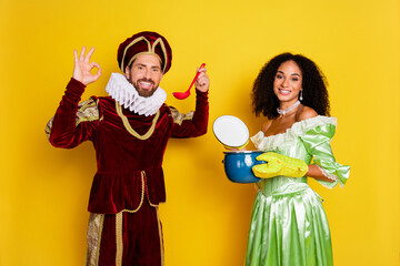 Elegant couple in retro costumes posing against vibrant yellow background with a modern twist