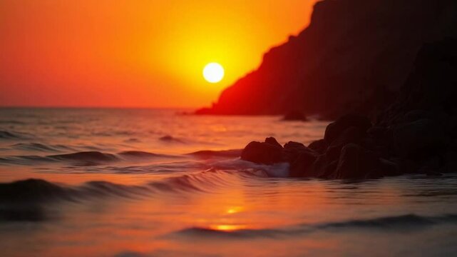A red burning sunset over sea with rocky volcanic cliff. Abstract nature summer ocean sea background. Small waves on golden warm water surface with bokeh lights from sun. Weather and climate change