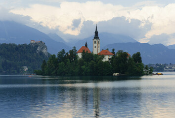 very small island on natural bled lake in summer with church in middle and beautiful green trees...